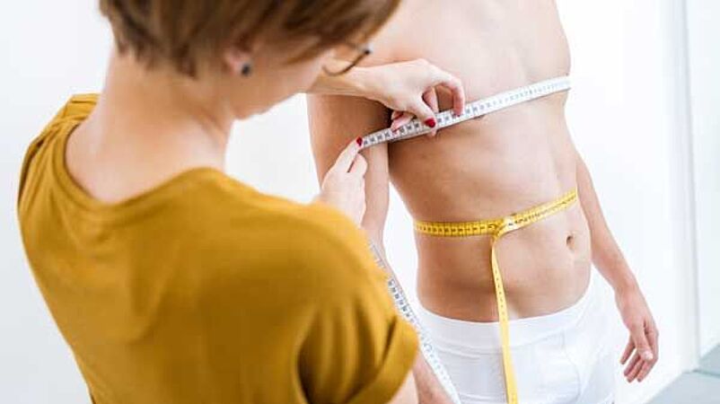 Apparel Engineer measuring torso of man for size table development